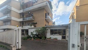 A multi-story residential building with balconies, a gated entrance, and potted plants. - Family apartment near the Vatican. Well connected. 2 terraces. WIFI. (Roma)