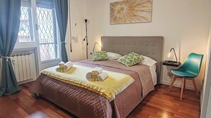A bedroom with a large bed, a bedside table, a chair, and a window with curtains. - Family apartment near the Vatican. Well connected. 2 terraces. WIFI. (Roma)