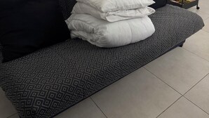 Un canapé gris à motifs, agrémenté de coussins blancs et noirs, est placé contre un mur blanc.