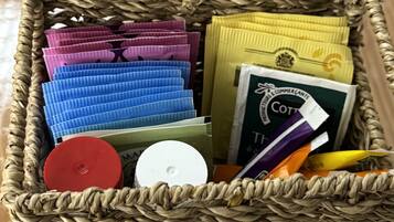 A wicker basket containing various items including colorful packets, a white circular object, and a book with a green cover.