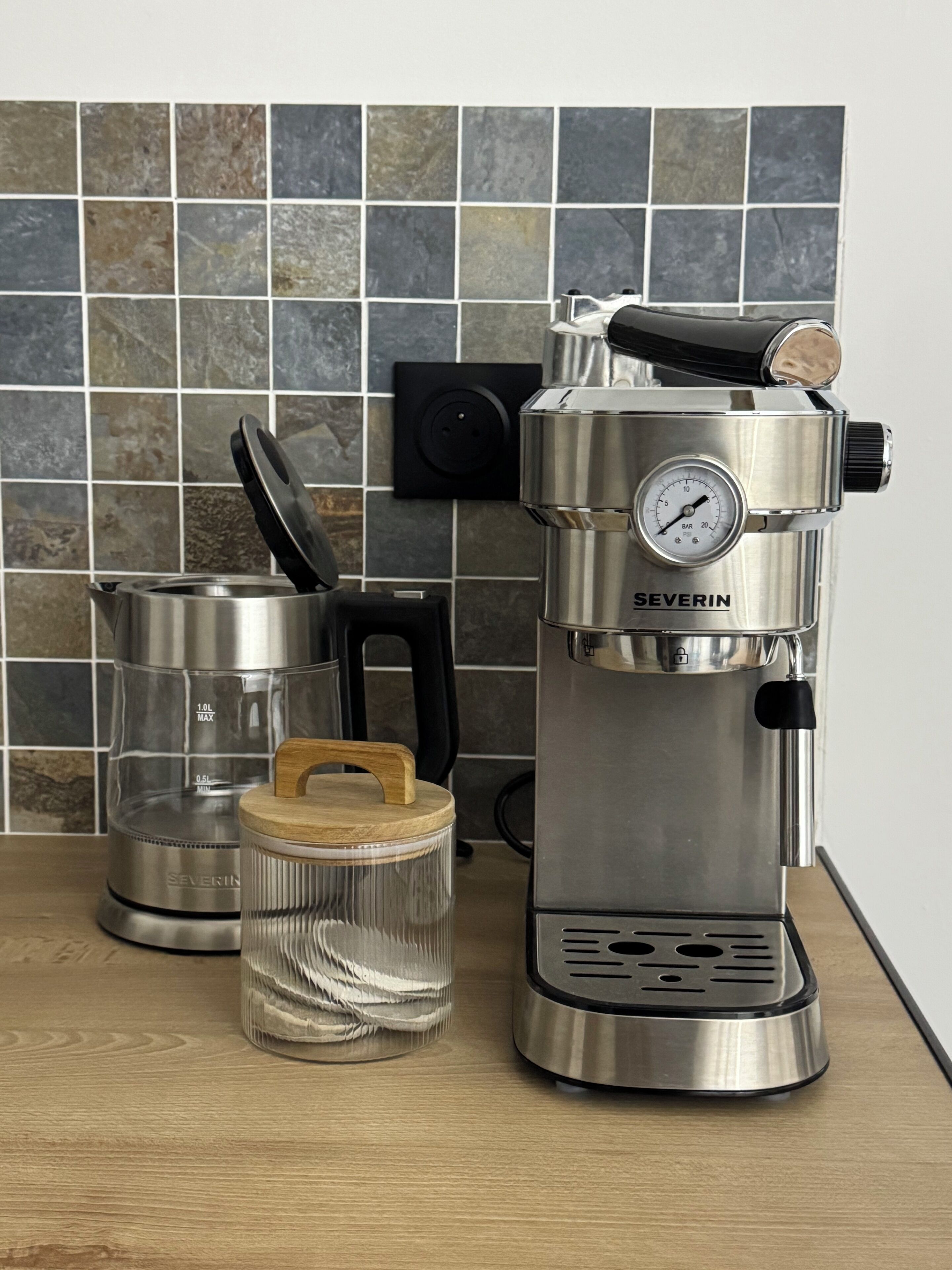 A coffee maker, a glass carafe, and a coffee grinder on a kitchen counter.