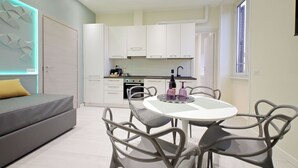 Una cocina moderna con armarios blancos, una mesa redonda para comer y sillas grises.