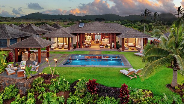 Un resort con varias edificaciones tipo bungalow, una piscina y exuberante jardinería.