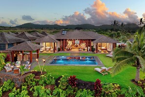 A resort with multiple bungalow-style buildings, a swimming pool, and lush landscaping.