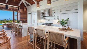 Una cocina moderna con una isla grande, vigas de madera en el techo e iluminación colgante.