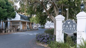 A sign for The Farm Village with directions to parking, hotel, shops, and food options.