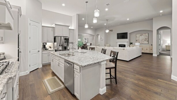 A spacious kitchen with white cabinetry, a granite countertop island, and a dining area with a sofa and chairs. - This beautiful 3200 SF single storey with loft backs onto a heavily treed forest (Dallas)