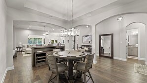 A spacious kitchen with a central island, a dining area with a round table, and a living area with a sofa and a coffee table. - This beautiful 3200 SF single storey with loft backs onto a heavily treed forest (Dallas)