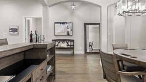 A modern kitchen with a wooden countertop, a built-in wine rack, and a dining area with a large table and chairs. - This beautiful 3200 SF single storey with loft backs onto a heavily treed forest (Dallas)