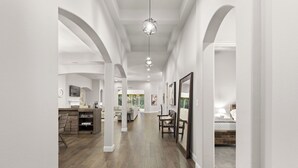 A spacious hallway with wooden flooring, white walls, and arched doorways leading to various rooms. - This beautiful 3200 SF single storey with loft backs onto a heavily treed forest (Dallas)