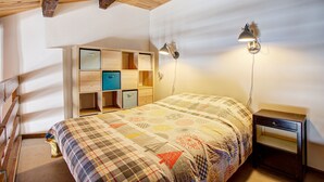 Ein Schlafzimmer mit einem Bett, einem Holz-Kopfteil, einem Einbauschrank mit mehreren Fächern und zwei Wandlampen.