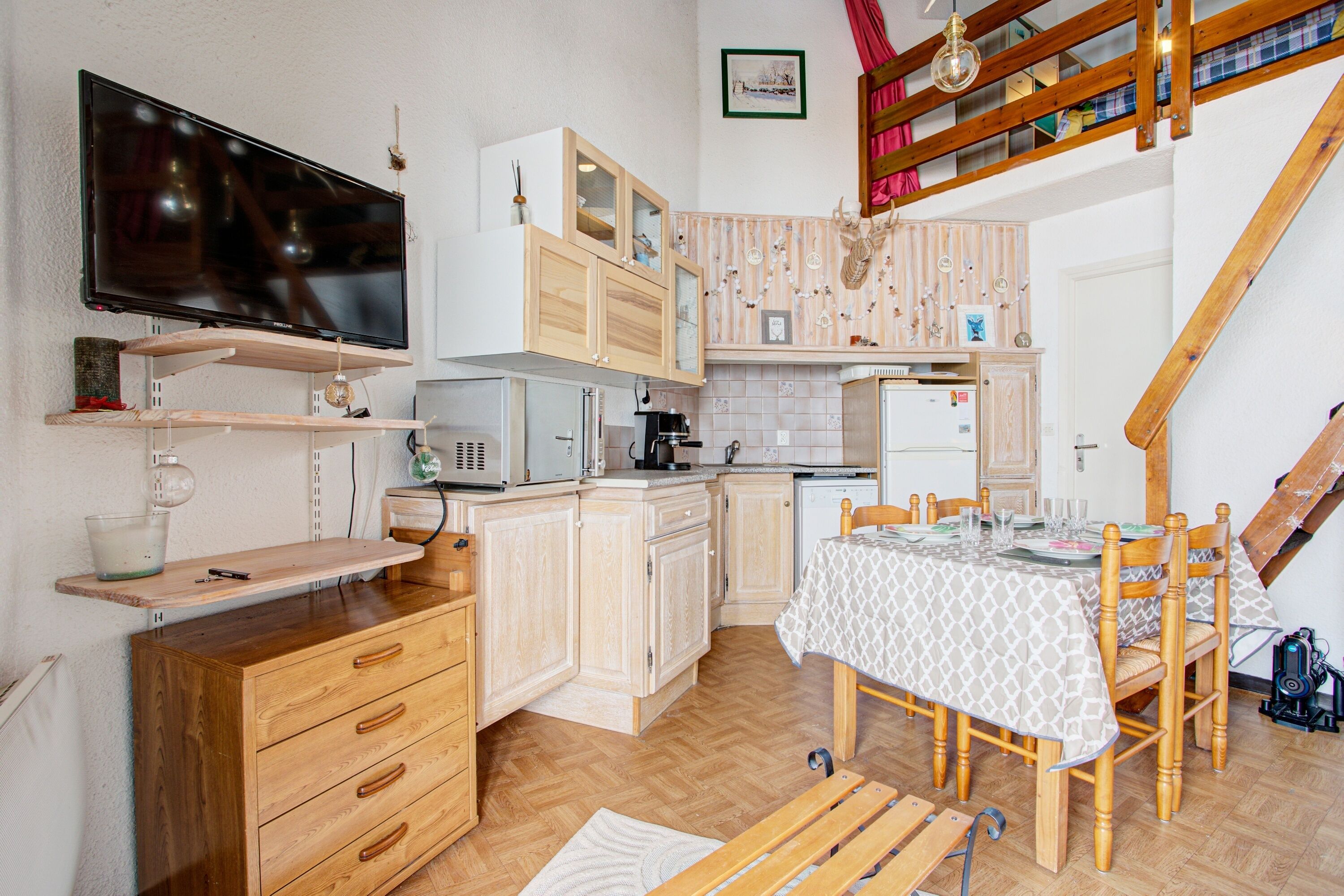 A compact kitchen with wooden cabinets, a built-in microwave, and a dining area with a table and chairs.