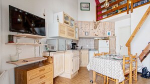 Eine kompakte Küche mit Holzausbau, einer integrierten Mikrowelle und einer Essecke mit Tisch und Stühlen.