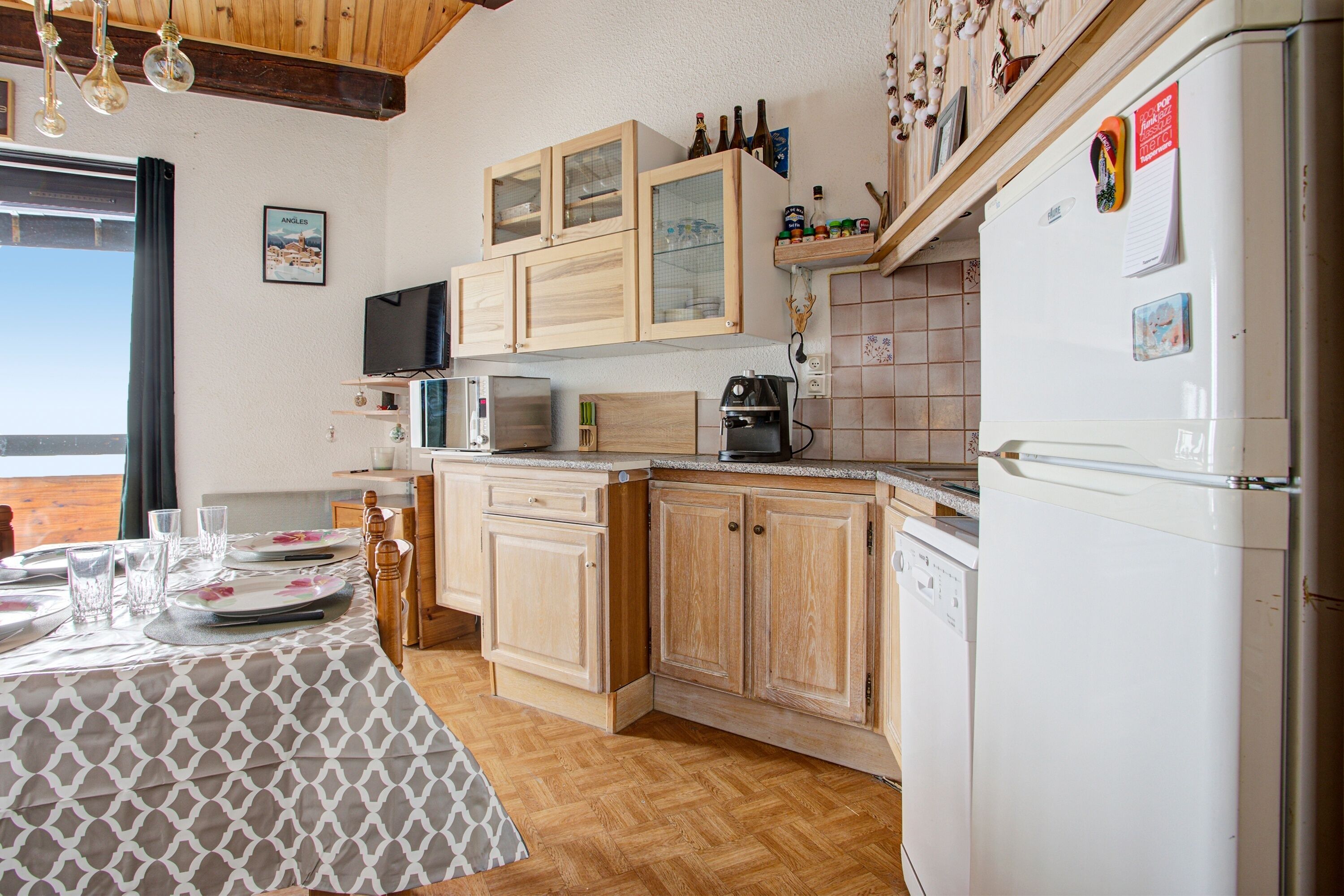 A kitchen with wooden cabinets, a microwave, a coffee maker, and a refrigerator.
