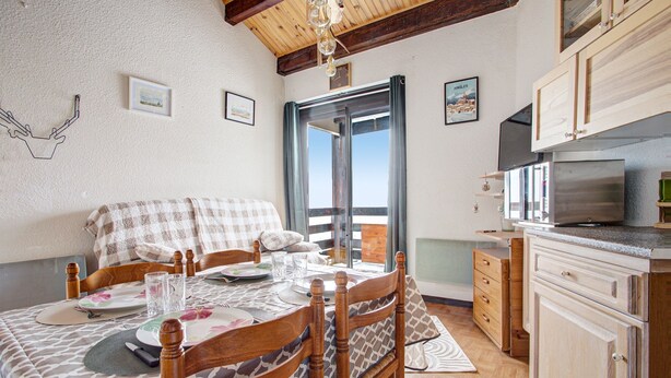 Una habitación acogedora con una cama, una mesa de comedor lista para dos personas, armarios de madera y un televisor.
