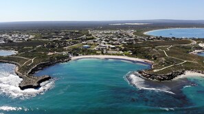An aerial view of a coastal area with a large bay, a beach, and a residential area with houses and roads. - Center Break beach stay (Green Head)
