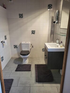 Ein Badezimmer mit Toilette, Waschbecken und Fliesenwänden.