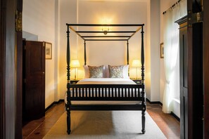 Un lit à baldaquin avec deux tables de chevet, un tapis et une porte sur le côté gauche.
