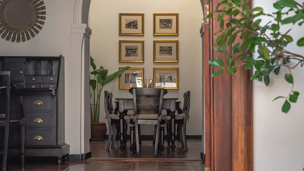 Un comedor con mesa y sillas, cuadros en la pared y una planta en maceta.