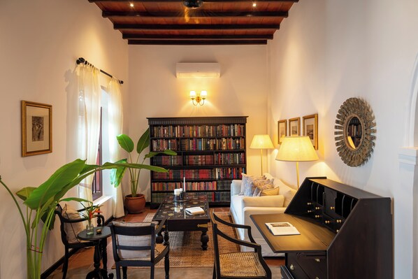 Un salon confortable avec une bibliothèque, un canapé, une table basse et une lampe.