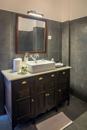 Une salle de bain avec un meuble-lavabo en bois foncé, un lavabo blanc et un miroir au-dessus.