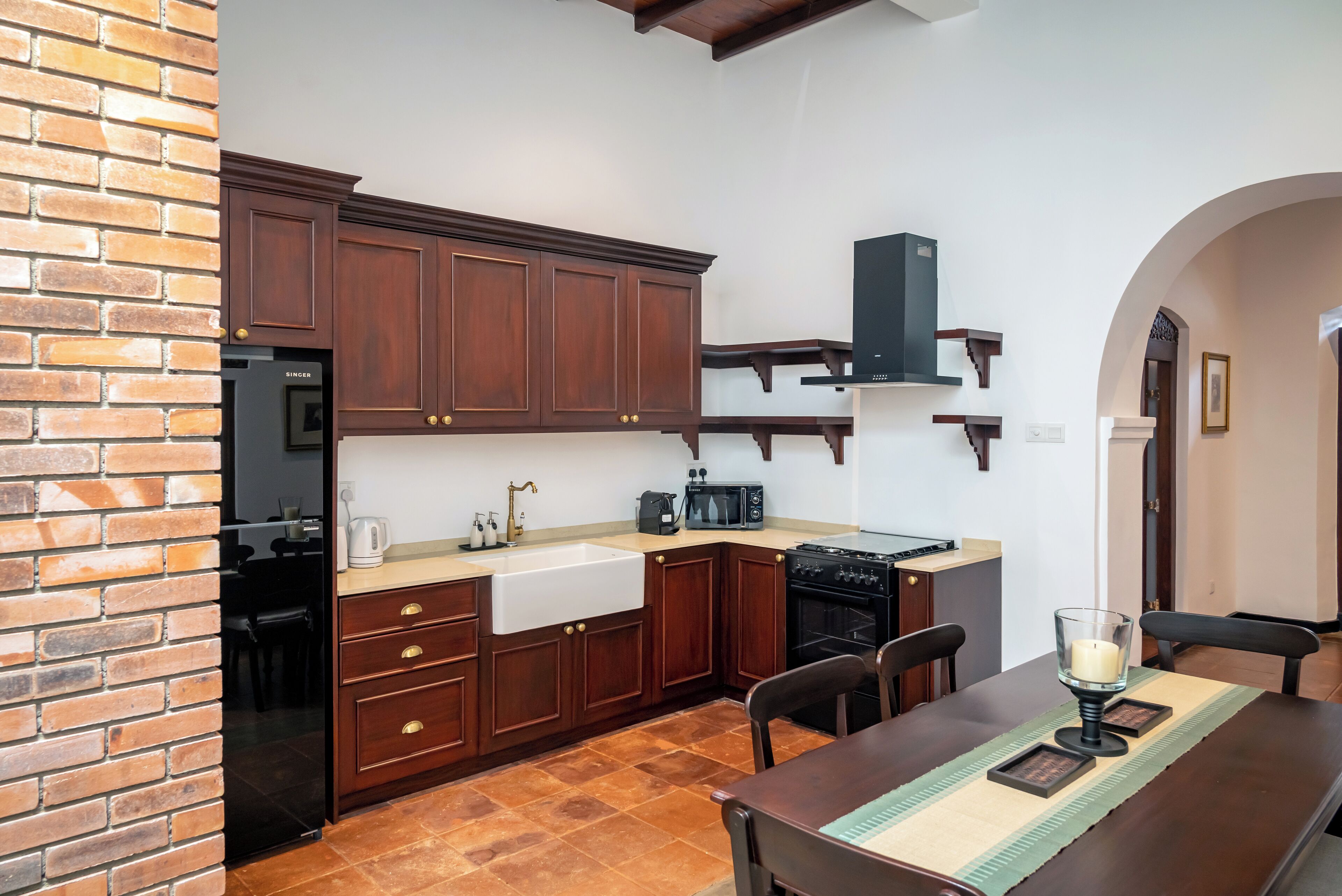 A kitchen with wooden cabinets, a sink, a stove, and a dining area with a table and chairs.