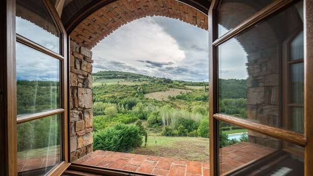 A room with a stone wall and a large arched window overlooking a green landscape. - Typical farmhouse in the heart of Chianti with private swimming pool  (Toscana)