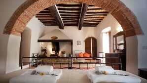 A bedroom with a brick archway, a bed with white linens, a wooden bench, and a stone fireplace. - Typical farmhouse in the heart of Chianti with private swimming pool  (Toscana)
