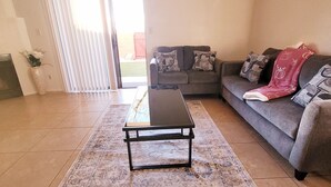 A living room with a sofa, a coffee table, and a patterned rug. - Cozy 2-bedroom townhome in charming Tucson with AC, WiFi. Located NW of Tucson . (Tucson)
