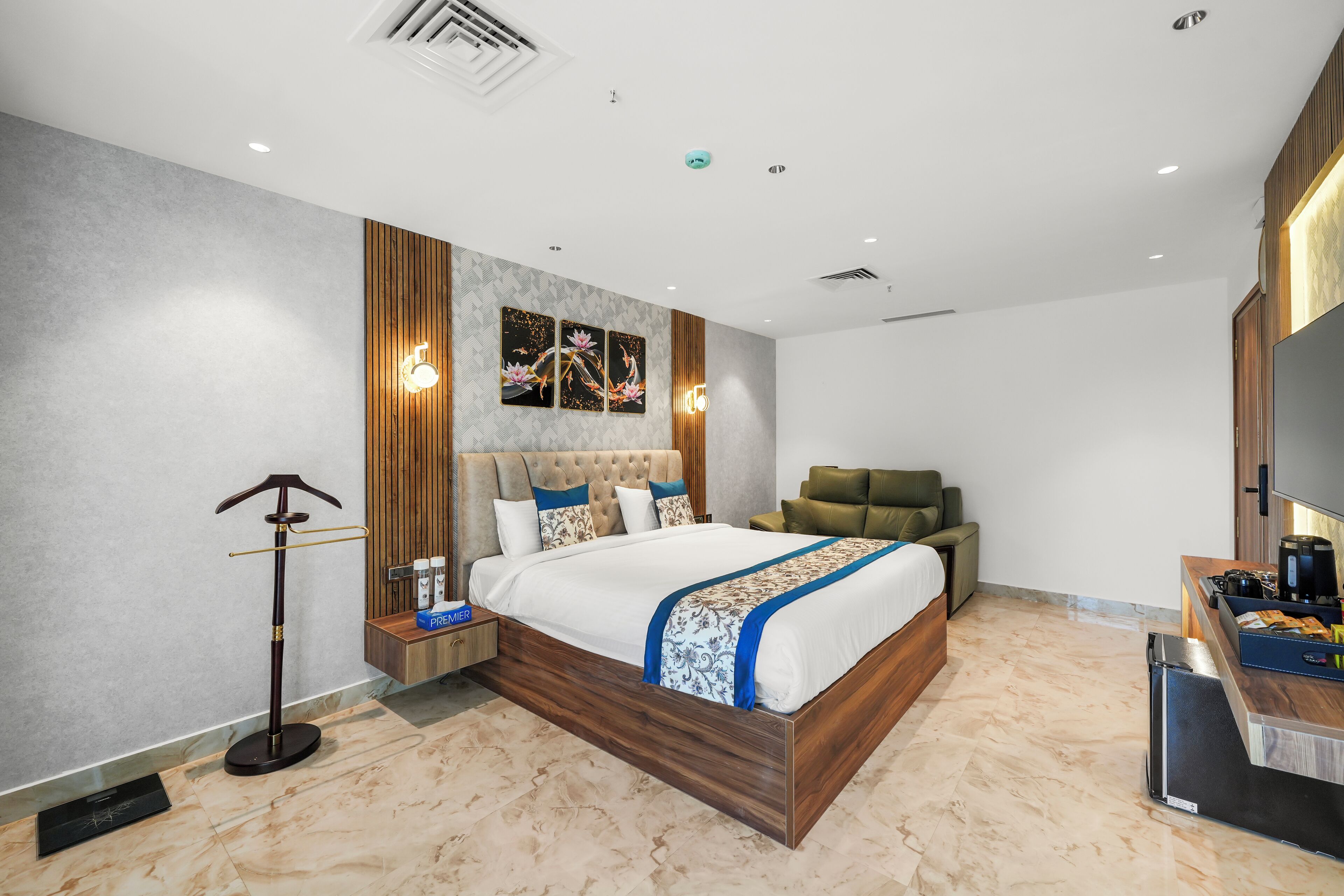 Una habitación de hotel moderna con una cama grande, un rincón de descanso y una kitchenette.