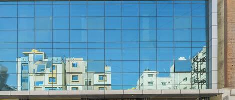 Un edificio moderno con amplios ventanales que reflejan edificios cercanos.