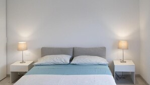 Ein Schlafzimmer mit einem Bett, zwei Nachttischen und zwei Lampen.