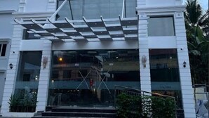 A hotel with a modern facade, a prominent entrance with a glass canopy, and a sign indicating it is a hotel. - Hotel VKJ Inn (Aluva)