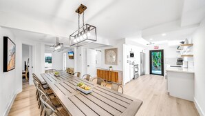 Una cocina moderna con una mesa de comedor de madera, armarios blancos y vistas al exterior.