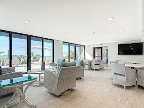 A spacious indoor area with wicker furniture, large windows, and a flat-screen TV.
