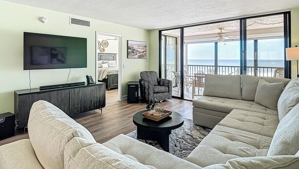 Una sala de estar con televisión de pantalla plana, un sofá, una mesa de centro y un balcón con vista al mar.