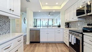Una cocina moderna con armarios blancos, lavavajillas, estufa y microondas.