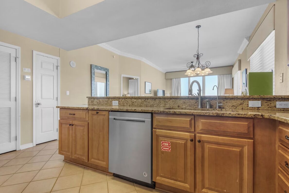 A kitchen with wooden cabinets, a dishwasher, and a chandelier.