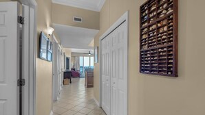 A hallway with white doors, a tiled floor, and a wall-mounted display of shells. - Inn At Summerwind 1405 (Navarre)