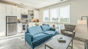 Una sala moderna con un sofá azul, un sillón gris y una mesa de centro.