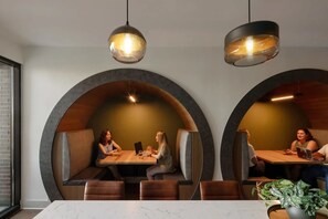 A modern restaurant with round booths and pendant lighting.
