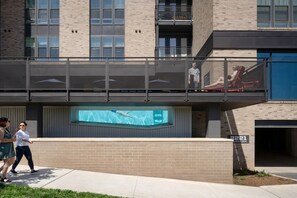 A modern building with a glass facade, a swimming pool, and a digital display.