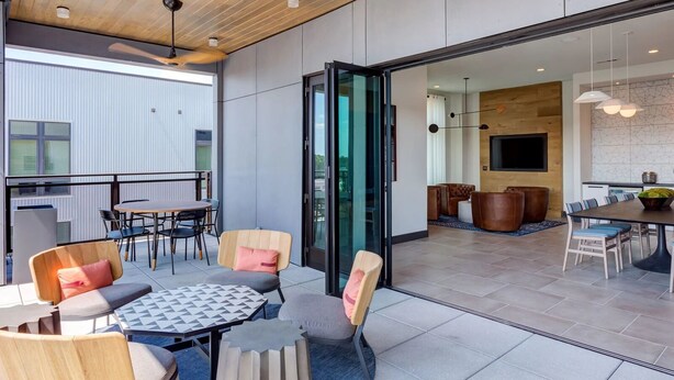Una habitación de hotel moderna con balcón, zona de comedor y sala de estar.
