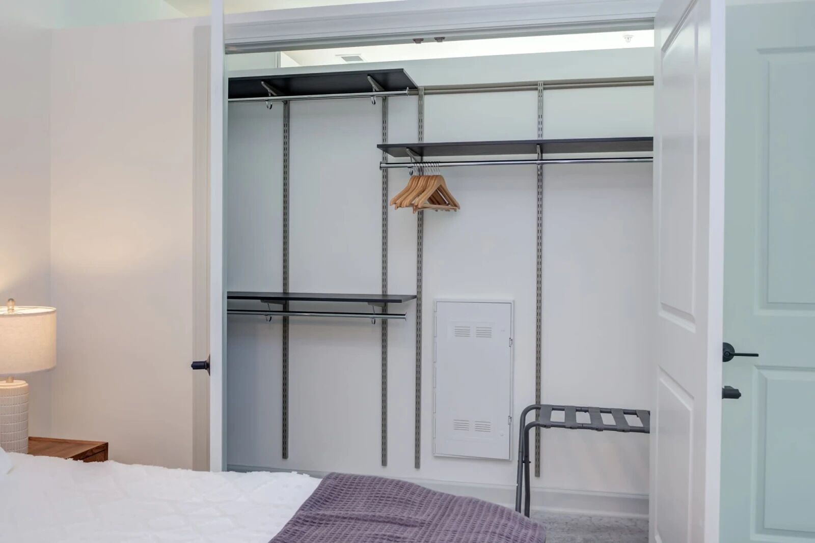 Un vestidor con estantes metálicos, una barra para colgar ropa y un armario.
