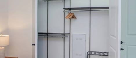 A walk-in closet with metal shelves, a hanging rod, and a storage cabinet.