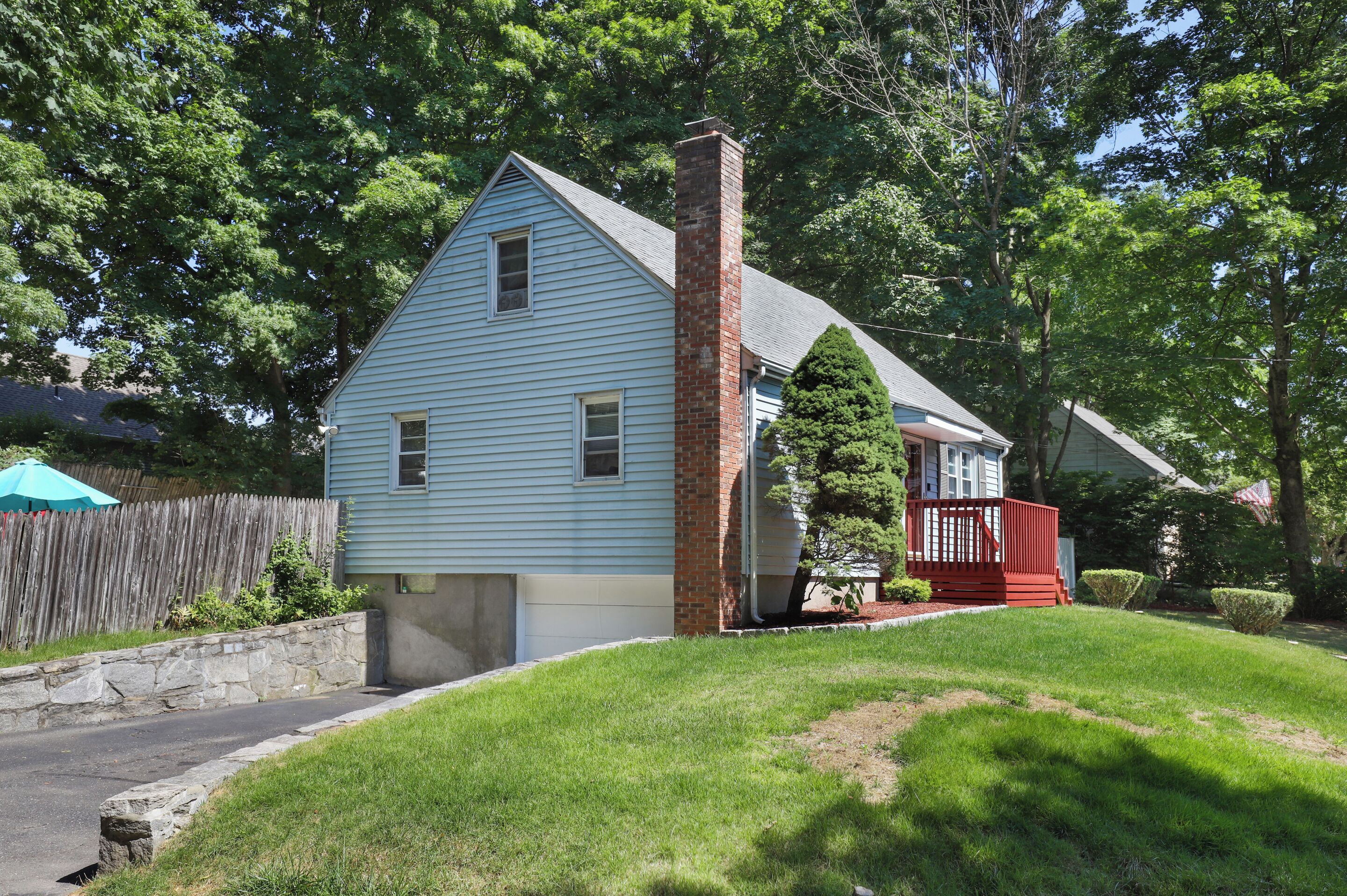 Ein eingeschossiges Haus mit Backsteinkamin, Garage und kleiner Terrasse.