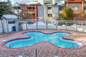 Ein Schwimmbecken mit Ziegelumrandung und Holzterrasse.
