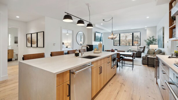 Een moderne keuken met een centraal eiland, houten keukenkastjes en hanglampen.