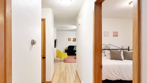 Ein schmaler Flur mit Holzboden, der zu einem Schlafzimmer mit Bett und Nachttisch führt.
