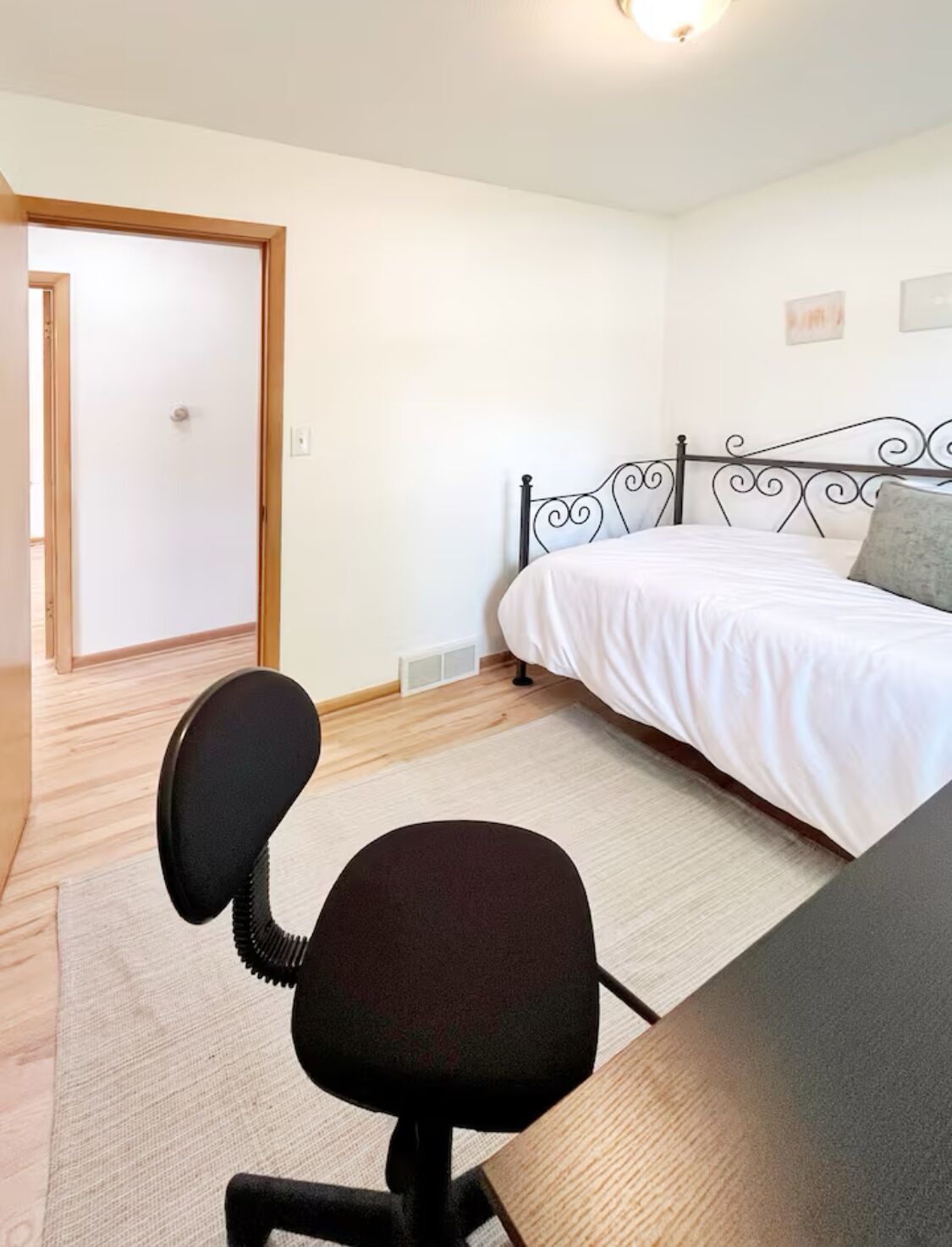 A bedroom with a bed, a desk, and a chair.